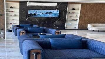 Una sala de estar moderna con un sofá modular, un televisor de pantalla plana montado en una pared de mármol y estanterías empotradas con objetos decorativos.
