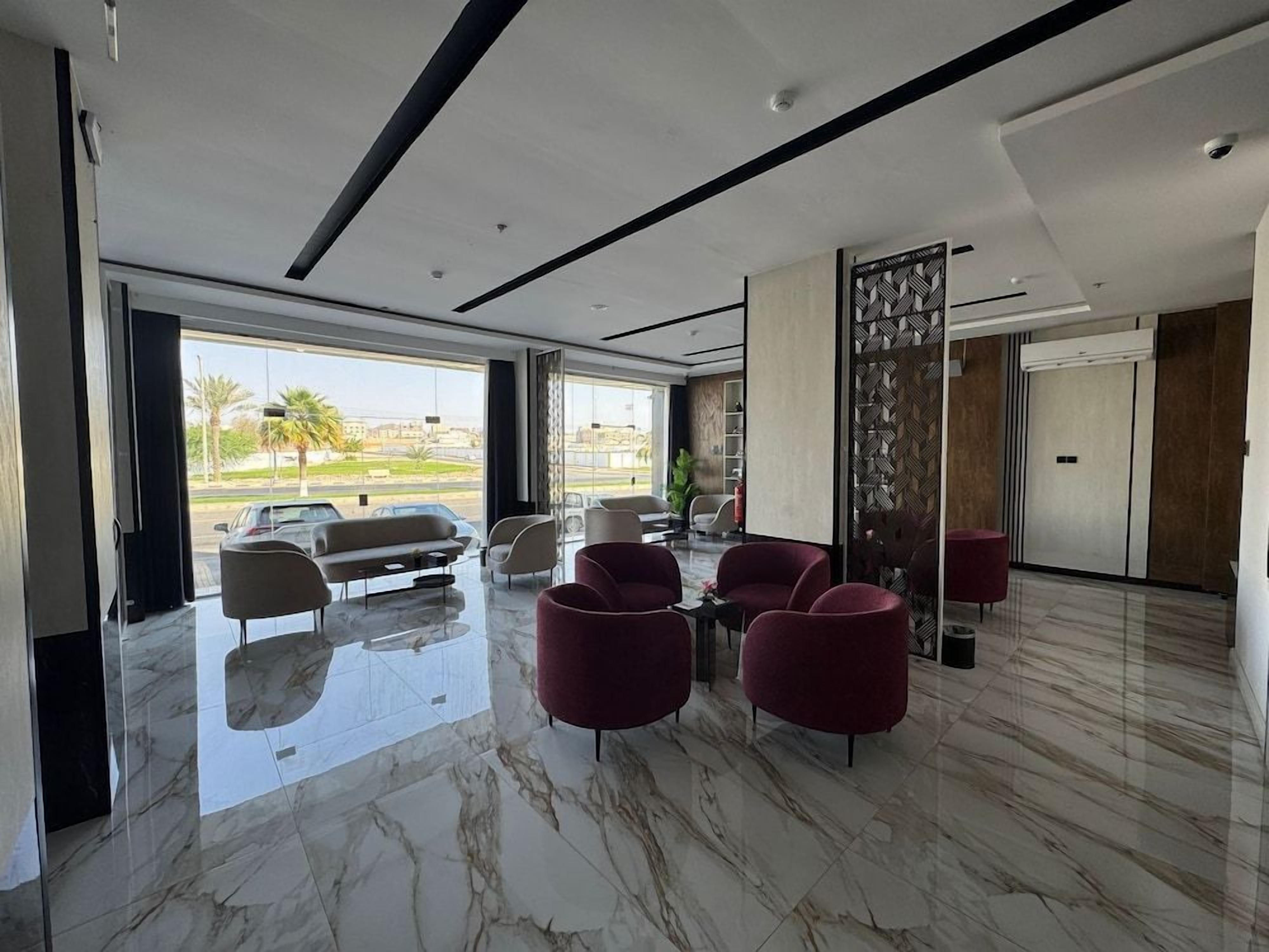 Un vestíbulo moderno con suelo de mármol, zona de estar con sofás y sillones, y vistas al exterior.