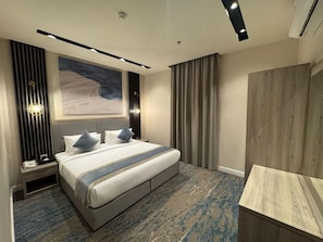 A modern hotel room with a large bed, a desk, and a view of a mountainous landscape. - Niyama Land Hotel (Umluj)