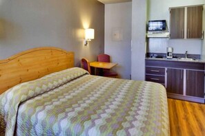 A hotel room with a bed, a small table, a chair, a microwave, and a kitchenette. - Spacious 1 Queen Bed | ADA/Tub, Nsmk (Dallas)
