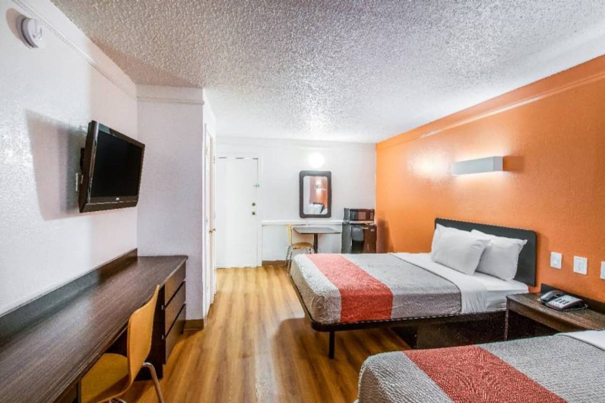 A hotel room with a bed, a desk, a chair, a television, and a small table.