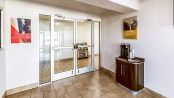 A hotel lobby with a reception desk, a coffee machine, and a magazine rack.