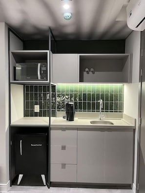 A compact kitchen with a microwave, coffee maker, and a sink. - Brava Mundo Boutique Hotel (Itajai)