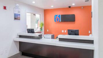 A reception desk with a digital display, a plant, and a wall-mounted sign.