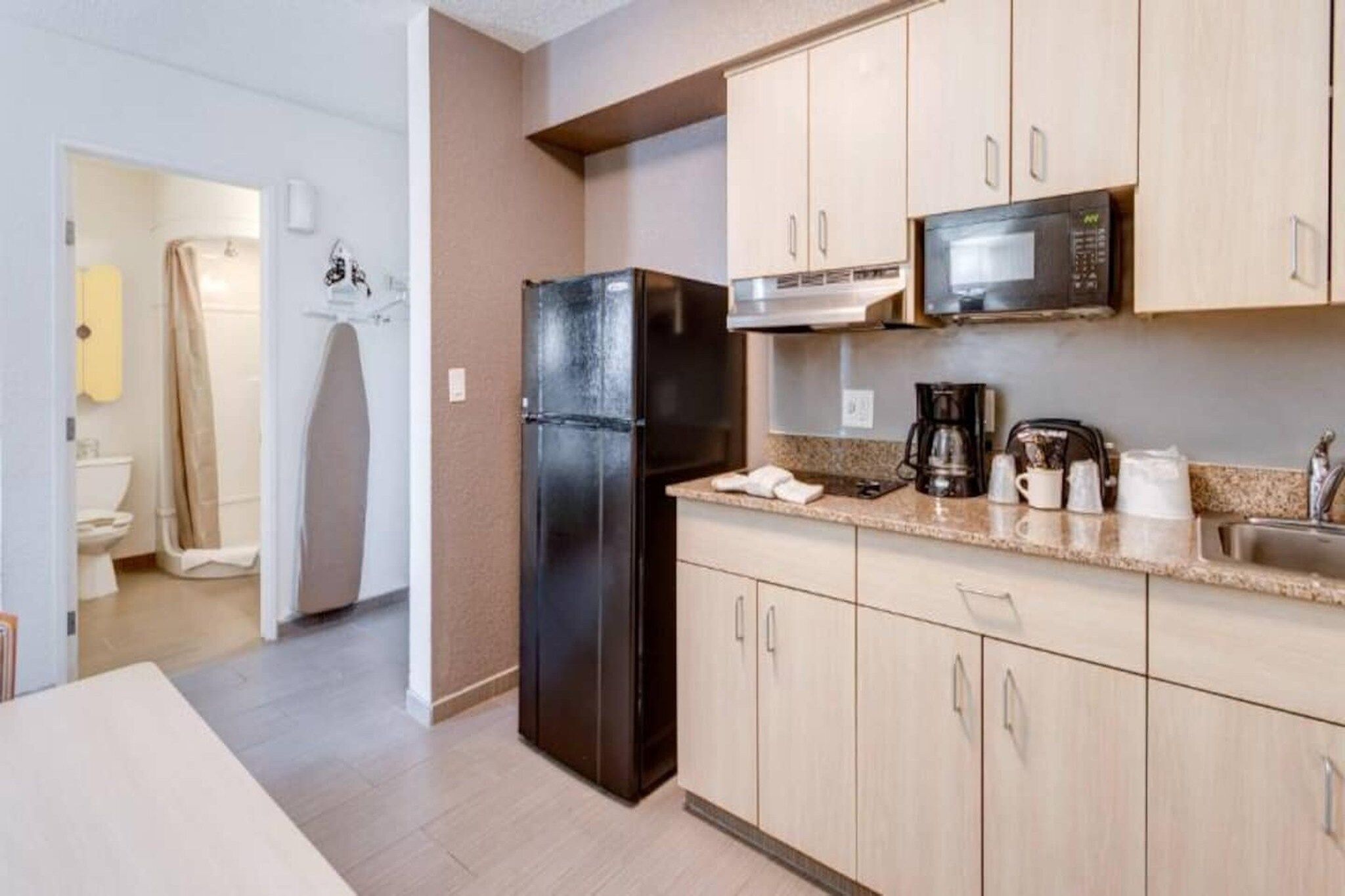 Una cocina compacta equipada con refrigerador, microondas, cafetera y pileta.