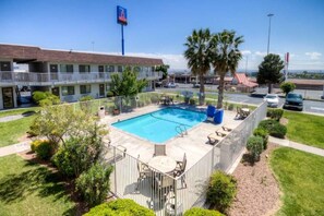 Een hotel met een zwembad, terras en uitzicht op de omgeving.