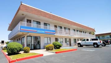 Un motel con un letrero que dice 'WELCOME', un estacionamiento y una camioneta pickup blanca.