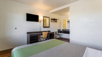 Una camera d'albergo con un letto, una scrivania, una sedia, una televisione e uno specchio.