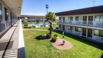 Un motel con piscina, una palmera y cielo despejado.