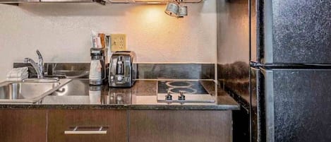 A kitchen with a microwave, toaster, and coffee maker on the counter, and a refrigerator to the right.