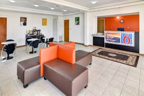 A hotel lobby with a reception desk, a seating area with orange and brown sofas, a small kitchenette, and a clock on the wall. - 2 Queen Beds | Nsmk, Micfridge (LINDALE)