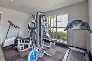 Una palestra con macchinari cardio, attrezzature per pesi e un tapis roulant.