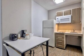 Eine kompakte Küchenzeile mit Kühlschrank, Mikrowelle und einem kleinen Esstisch mit Stühlen.