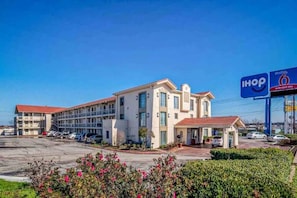 Hotel com vários andares e estacionamento à frente.