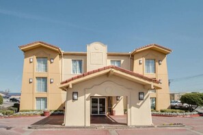 Ein mehrstöckiges Hotel mit einem zentralen Eingang, großen Fenstern und einem flachen Dach.