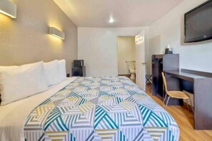 Une chambre d’hôtel comprenant un lit, un bureau, une chaise, une télévision et une armoire.