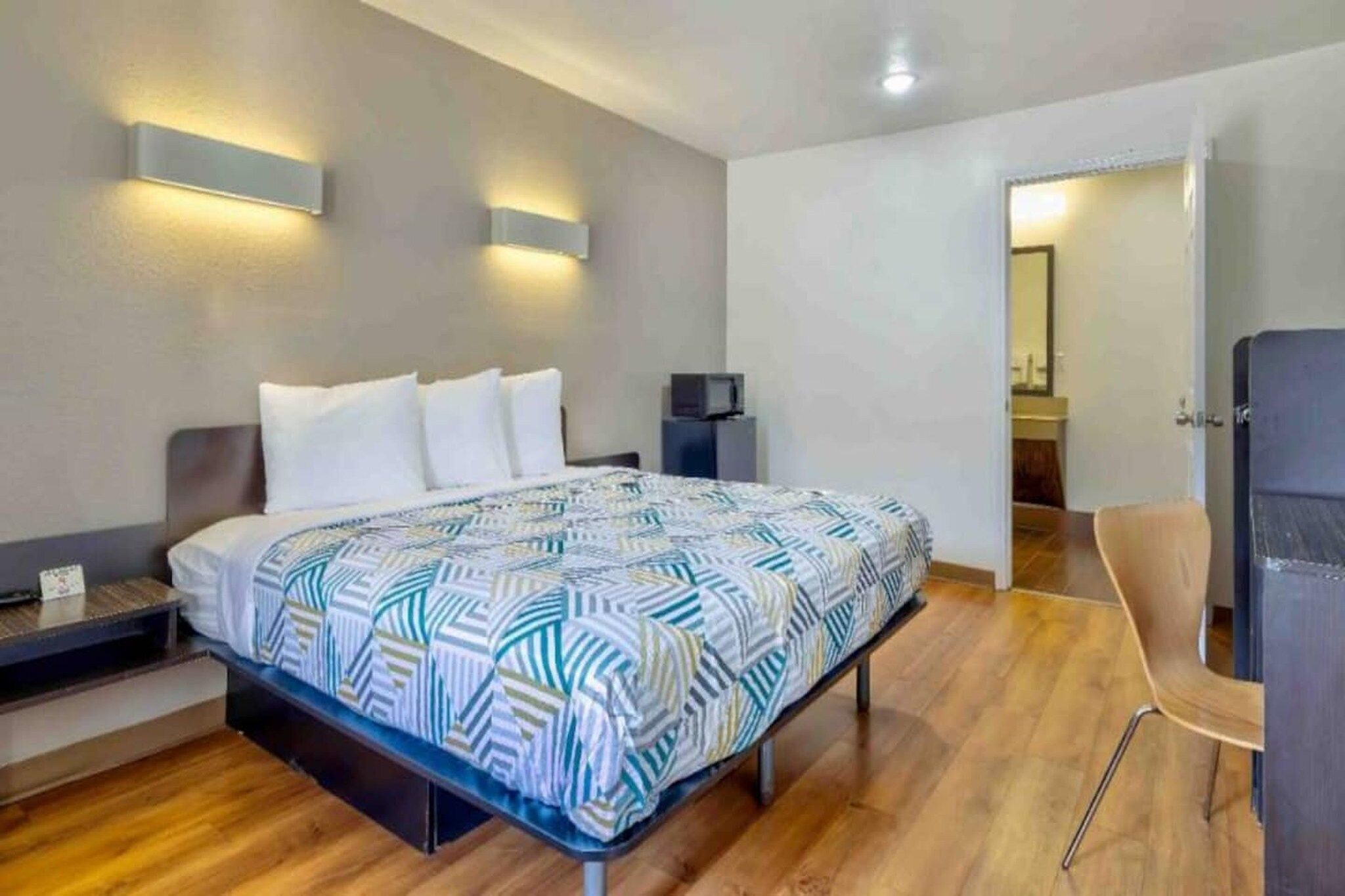 Ein modernes Schlafzimmer mit Bett, Nachttischen, einem Flachbildfernseher und einem Sessel.