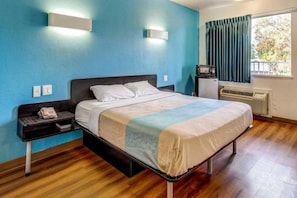 Una cama individual en una habitación con pared azul, un calentador y una ventana con cortinas.