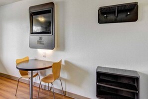 Une pièce moderne avec une table ronde et deux chaises, un téléviseur fixé au mur et une bibliothèque intégrée.