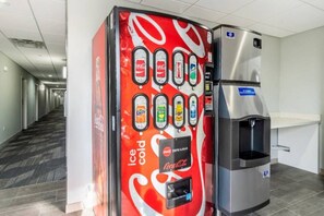 Ein Getränkeautomat mit Coca-Cola-Logo und Wasserspender in einem Flur.