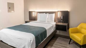 A hotel room with a bed, bedside tables, a chair, and a wall-mounted phone.