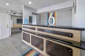A reception desk with a number '6' sign, a flat-screen TV, and a security camera. - 2 Queen Beds | Smoking, Kitchen (Dallas)