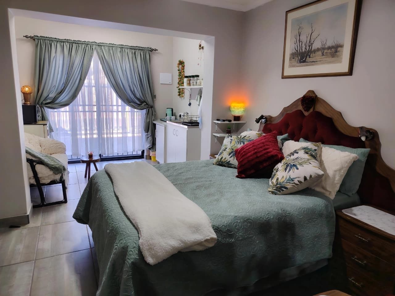 A bedroom with a bed, bedside table, lamp, and a view of the bathroom.