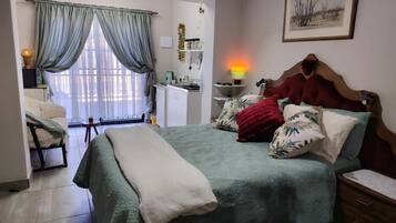 A bedroom with a bed, bedside table, lamp, and a view of the bathroom.