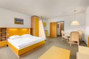 A hotel room with a bed, a desk, a chair, a lamp, and a painting on the wall. - Studio im IFA Fehmarn Ferienpark (Fehmarn)