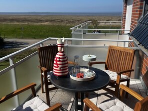 Ein Balkon mit Tisch, Stühlen und einer dekorativen Flasche.