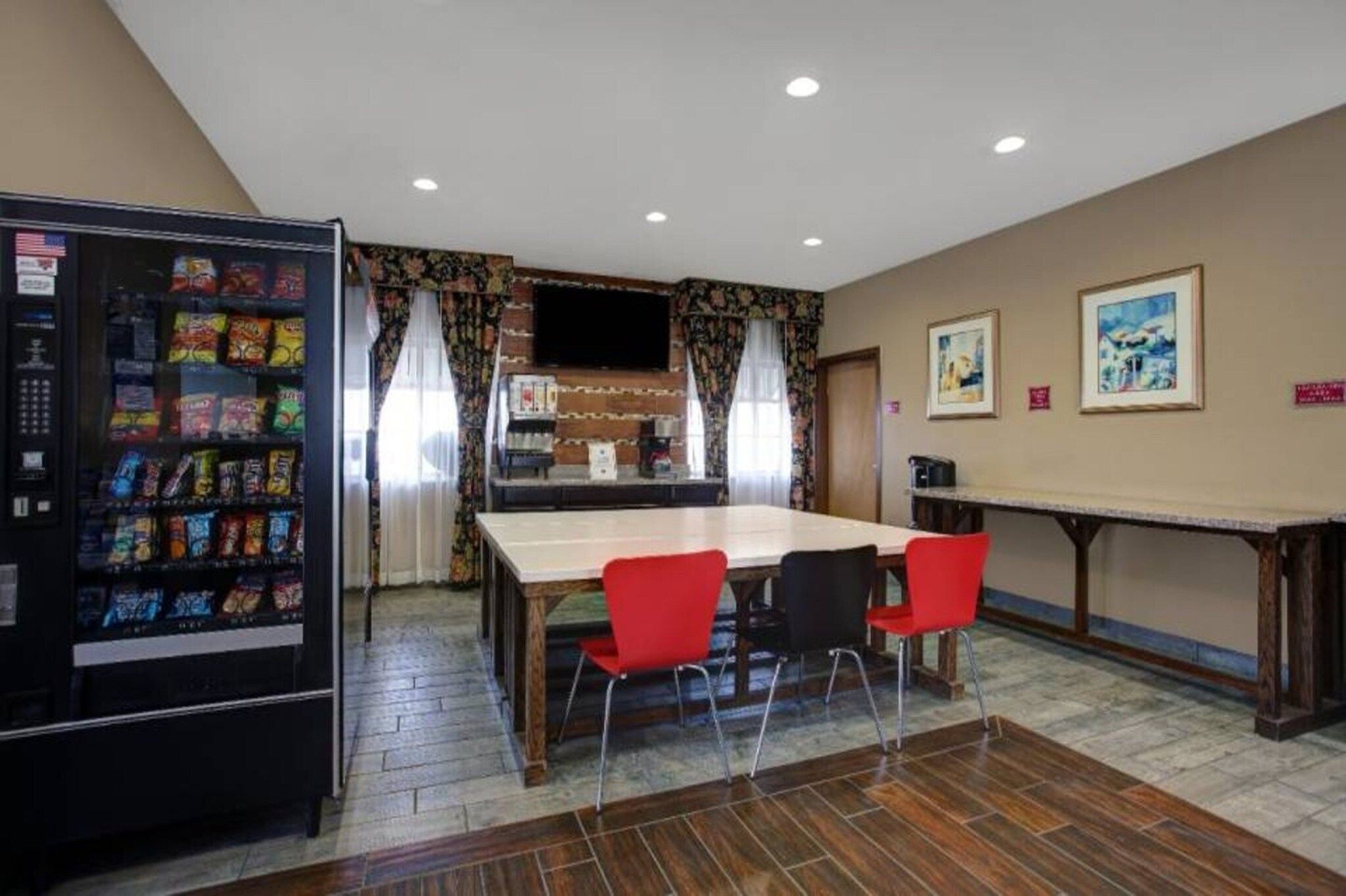 Una habitación con mesa de comedor, sillas, refrigerador y televisor.