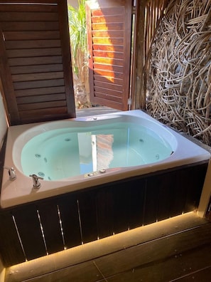 A hot tub with a wooden frame and a glass enclosure, surrounded by a wooden deck and a decorative wall. - Casa K u Hotel (Dzemul)