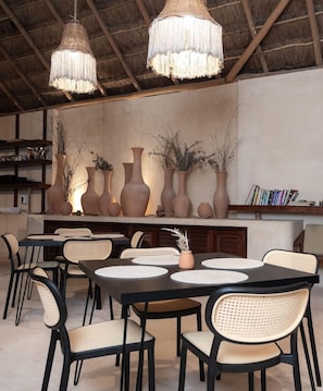 A dining area with tables and chairs, decorative vases, and hanging light fixtures. - Casa K u Hotel (Dzemul)