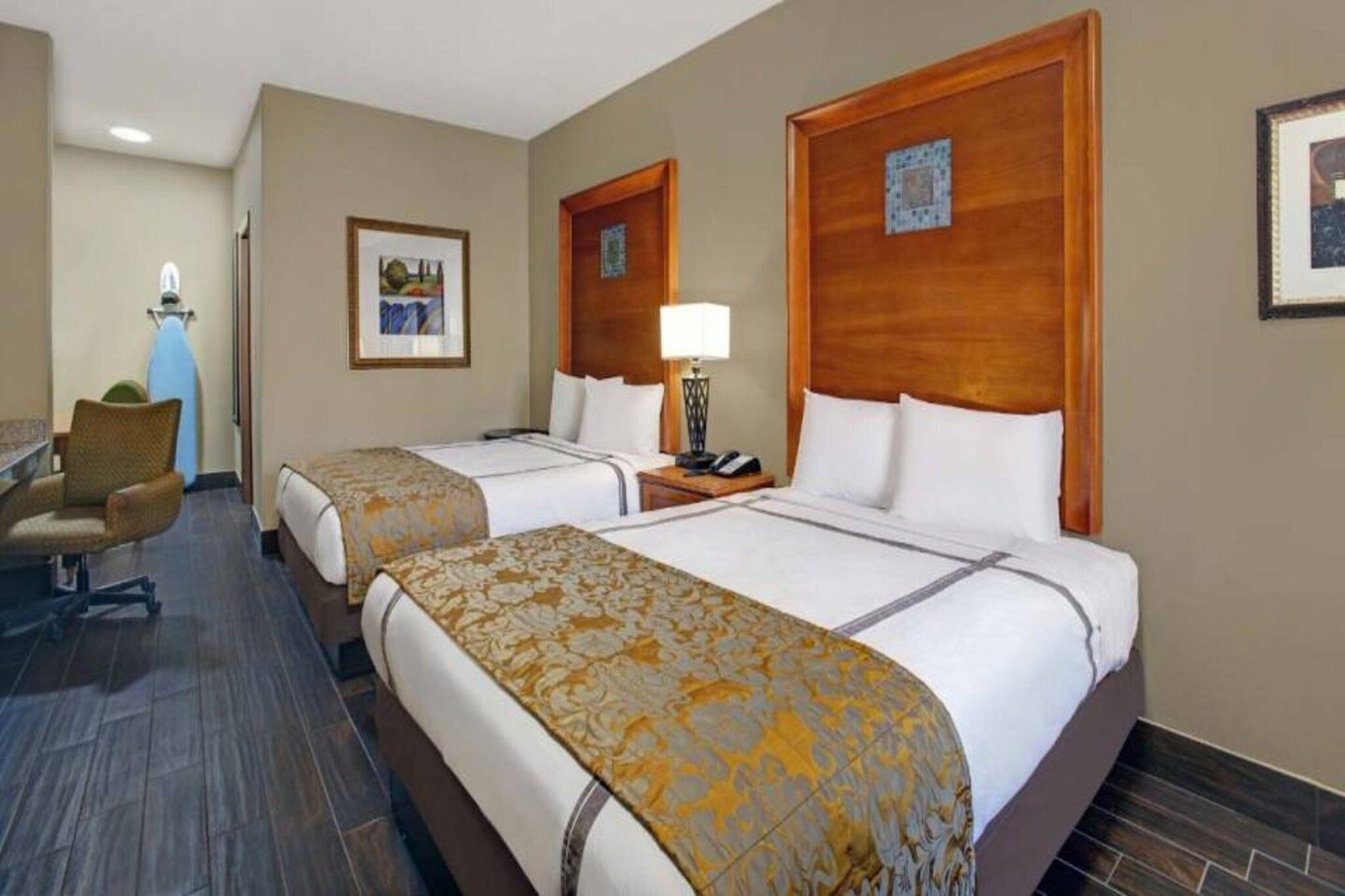 Een hotelkamer met twee bedden, een bureau, een stoel en een lamp.