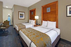 Une chambre d’hôtel avec deux lits, un bureau, une chaise et une lampe.