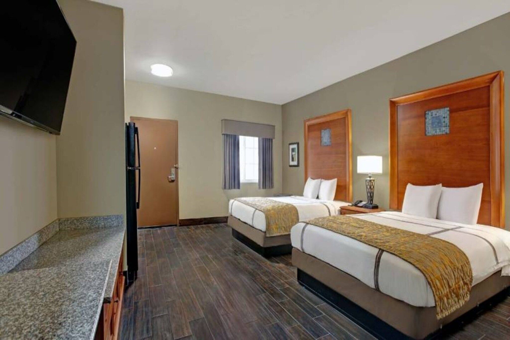 Une chambre d’hôtel avec deux lits, une télévision, un bureau et une porte.