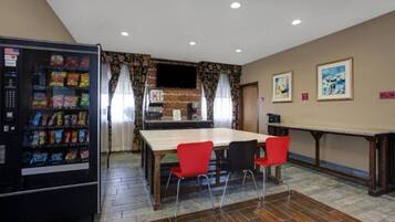 Una habitación con mesa de comedor, sillas, refrigerador y televisor.
