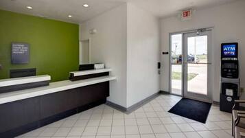 A reception area with a green wall, a reception desk, an exit door, and an ATM machine.