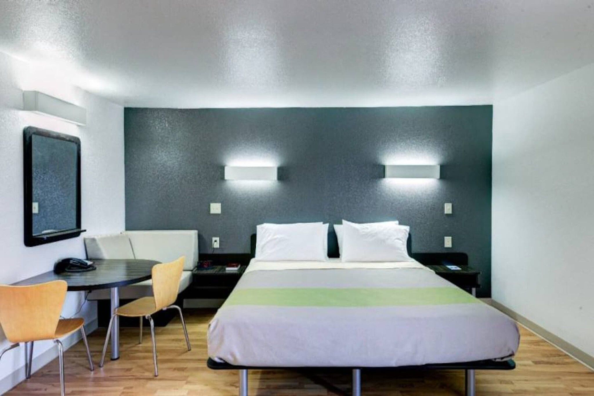 Une chambre d’hôtel équipée d’un lit, d’un bureau, d’une chaise et de deux lampes fixées au mur.