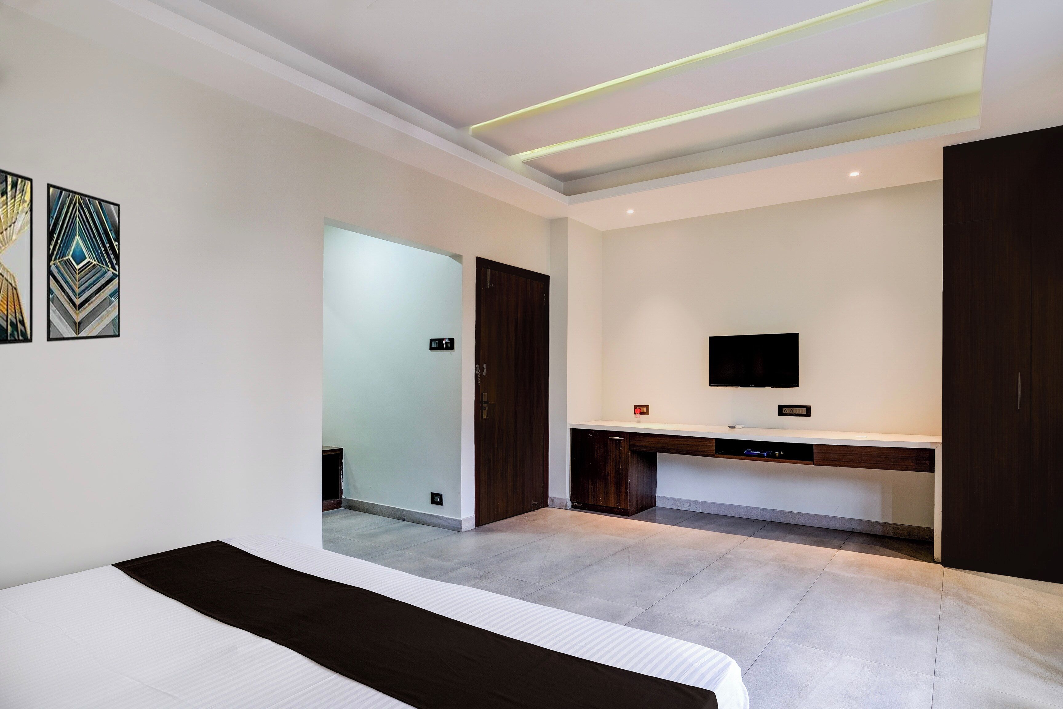A modern bedroom with a bed, a desk, and a television.