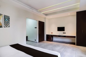Un dormitorio moderno con cama, escritorio y televisor.