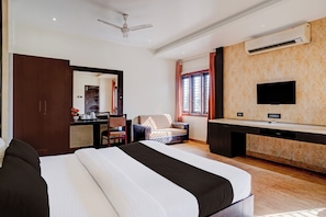 Una habitación de hotel con cama, escritorio, silla y televisor en la pared.