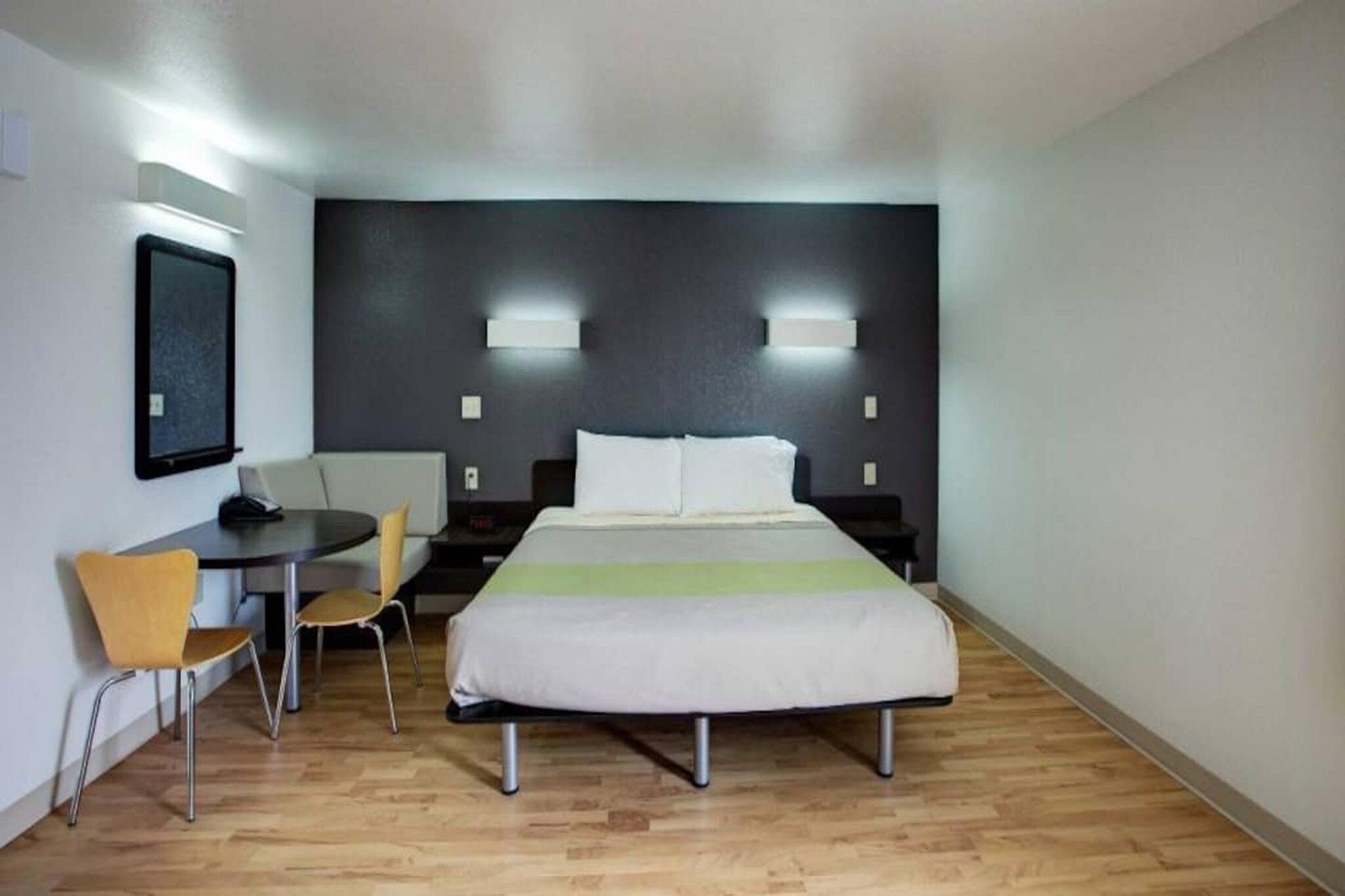 Een hotelkamer met een bed, nachtkastjes, een bureau, een stoel en een kleintje tafel.