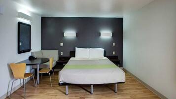 Een hotelkamer met een bed, nachtkastjes, een bureau, een stoel en een kleintje tafel.