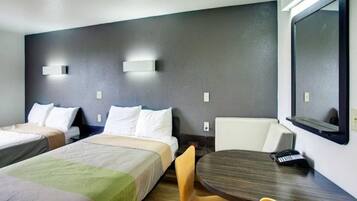 A hotel room with two beds, a round table, and a chair.