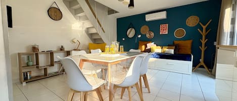 A modern living space with a dining area, staircase, and a blue accent wall.