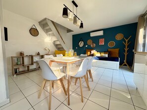 A modern living space with a dining area, staircase, and a blue accent wall. - Holiday Home 'Maison De La Gardiole' with Shared Pool, Wi-Fi and Air Conditioning (Frontignan)