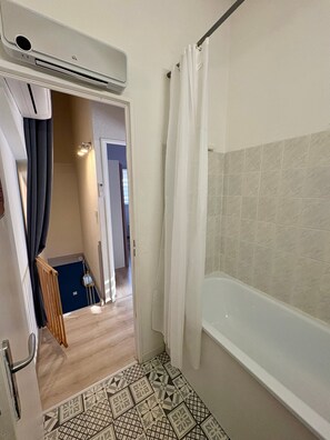 A bathroom with a bathtub, a shower curtain, and a tiled floor. - Holiday Home 'Maison De La Gardiole' with Shared Pool, Wi-Fi and Air Conditioning (Frontignan)
