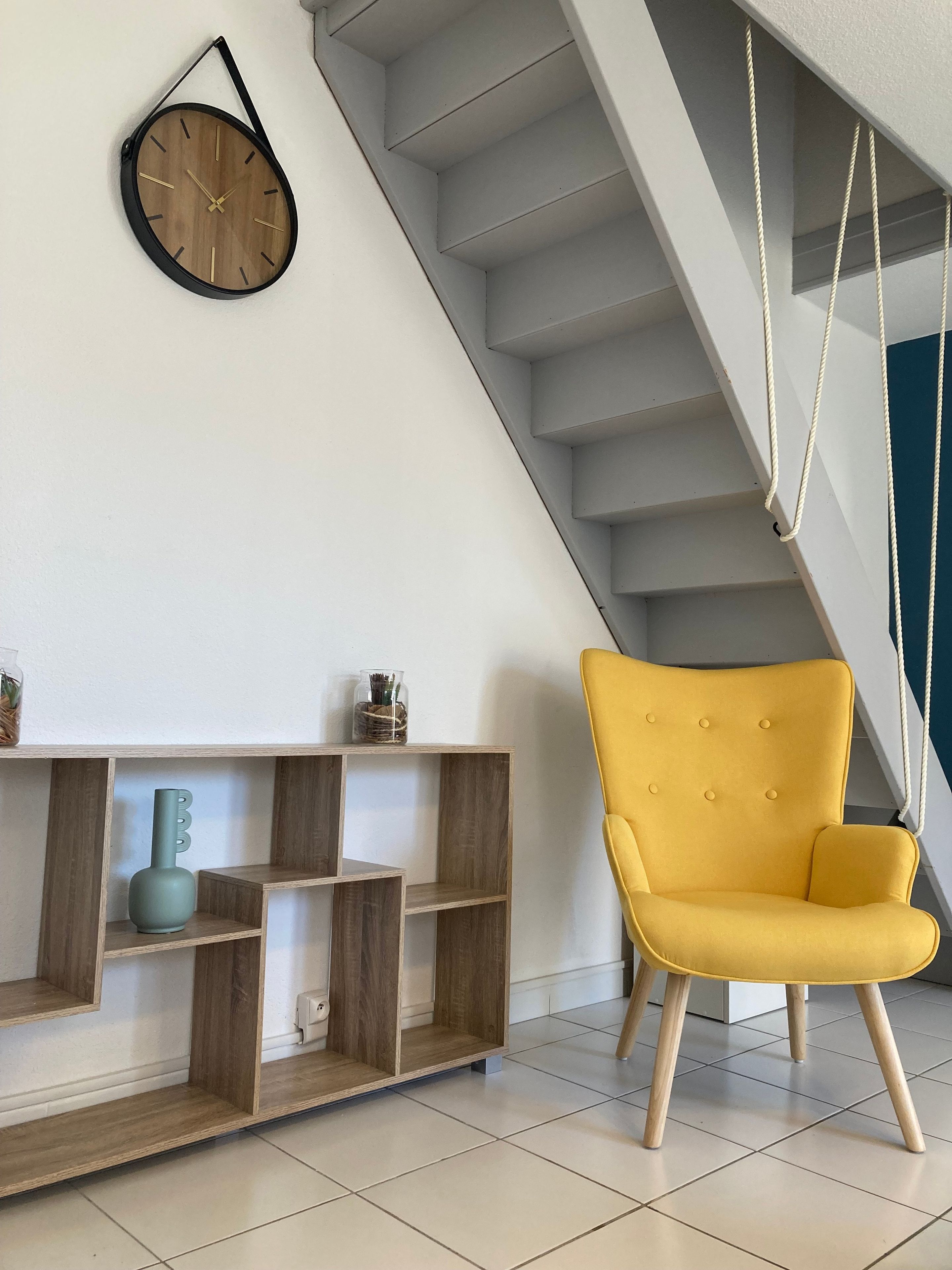 Ein modernes Interieur mit einem Holzkonsolentisch, einem gelben Sessel und einer Treppe.