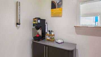 A coffee machine, a basket with utensils, and a window with a view.